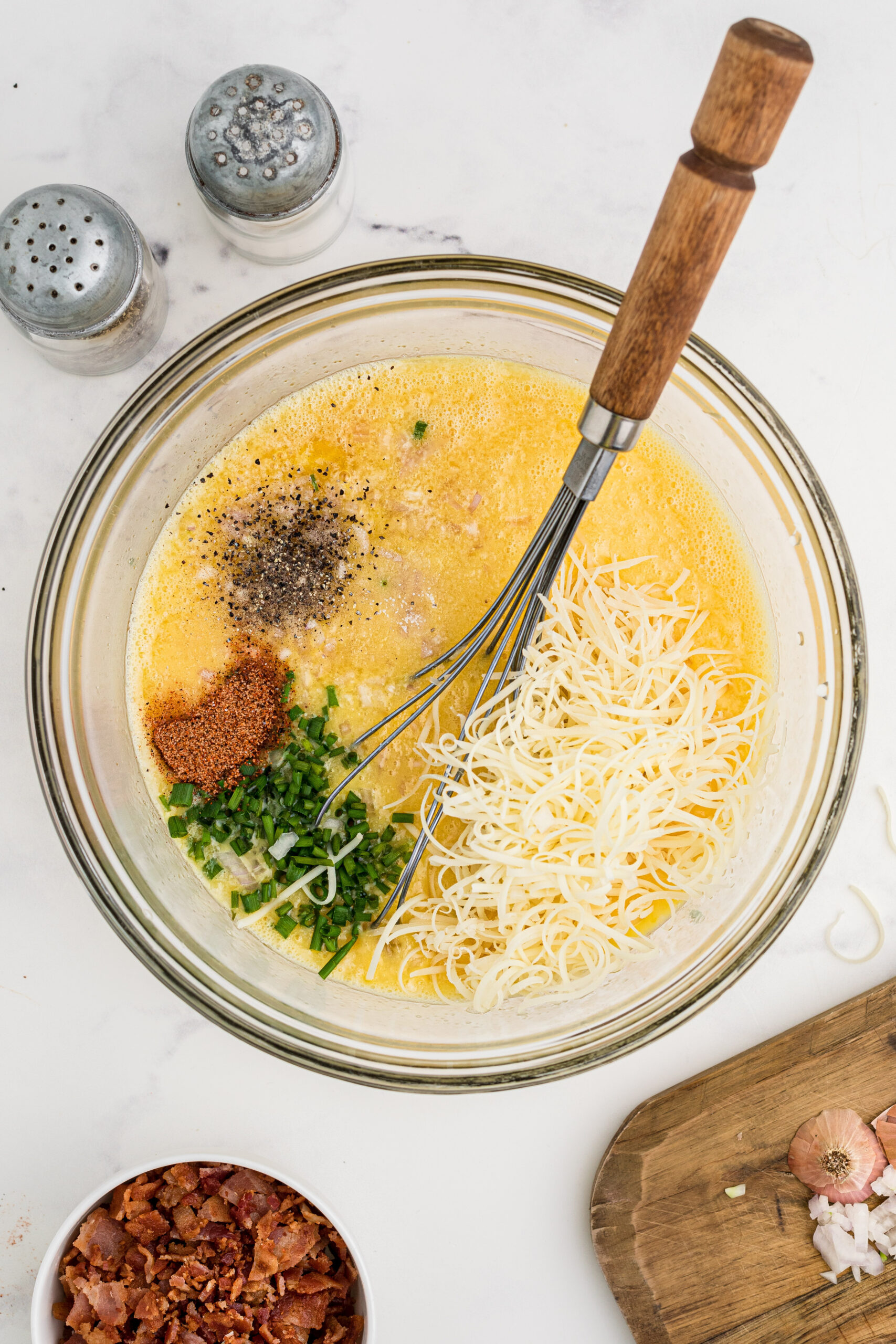 Adding melted butter, chives, cheese and seasoning to the egg mixture