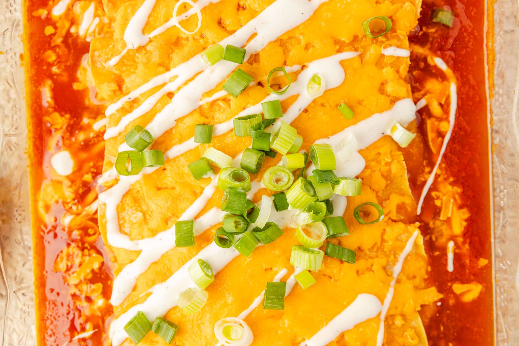 Close up of baked buffalo chicken enchilada, topped with ranch and green onions