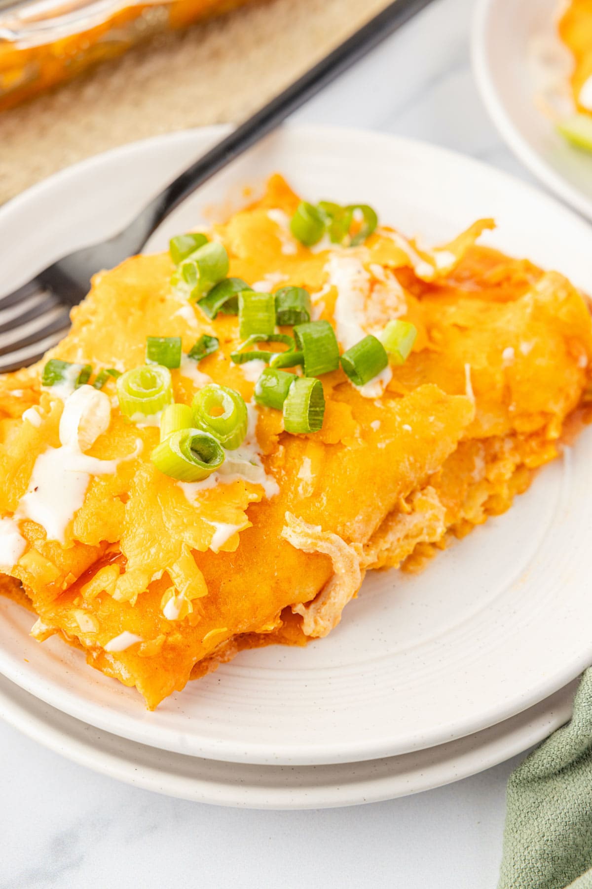 Two buffalo chicken enchiladas on a plate with a fork
