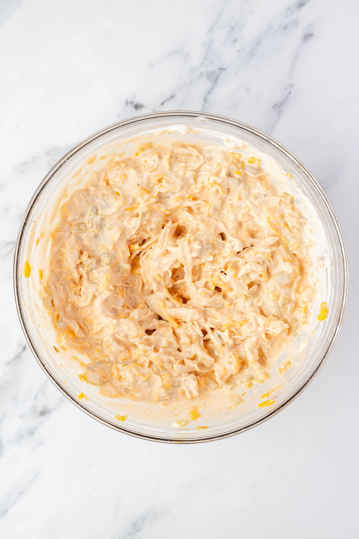 Shredded chicken, sour cream, ranch, cheddar cheese, diced chili peppers, hot sauce in a mixing bowl