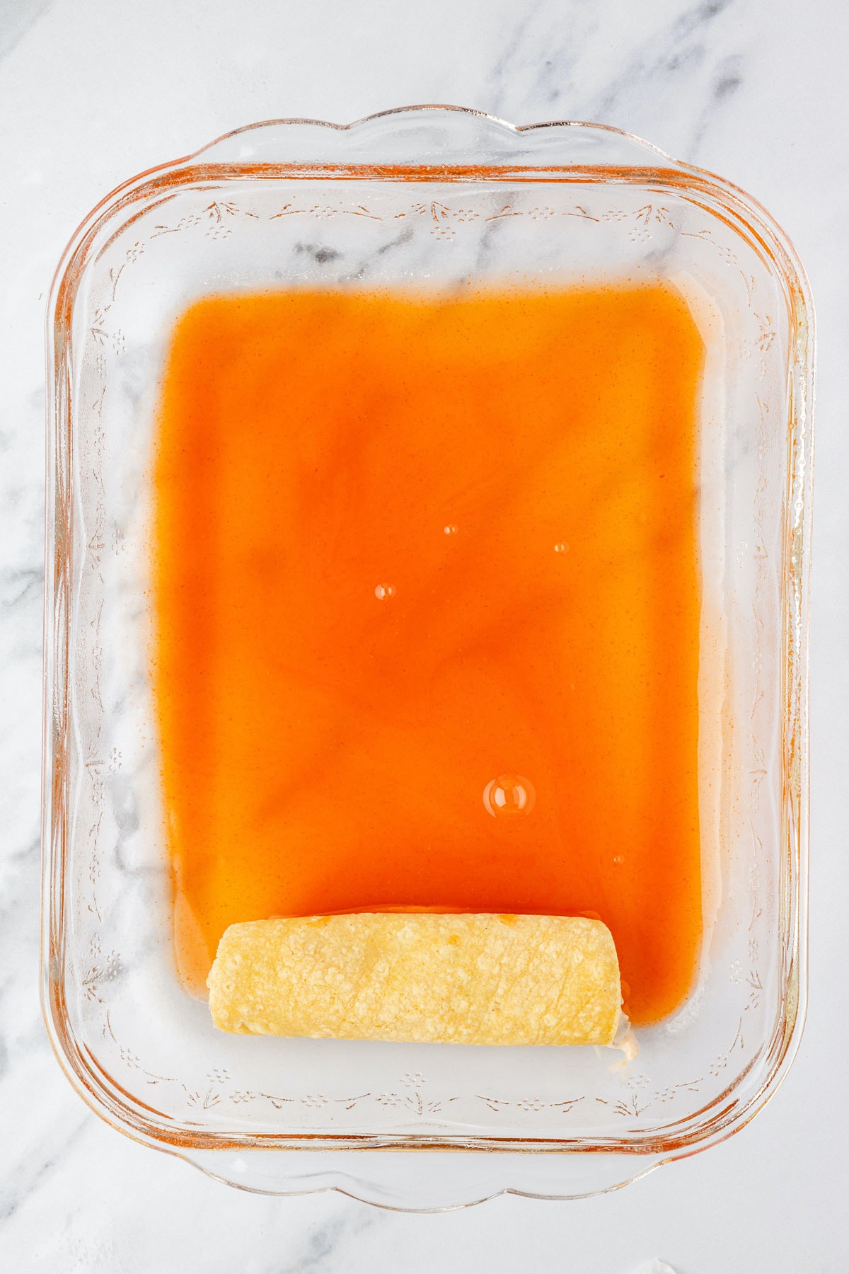 Chicken mixture placed inside of tortilla, rolled up and placed in baking dish