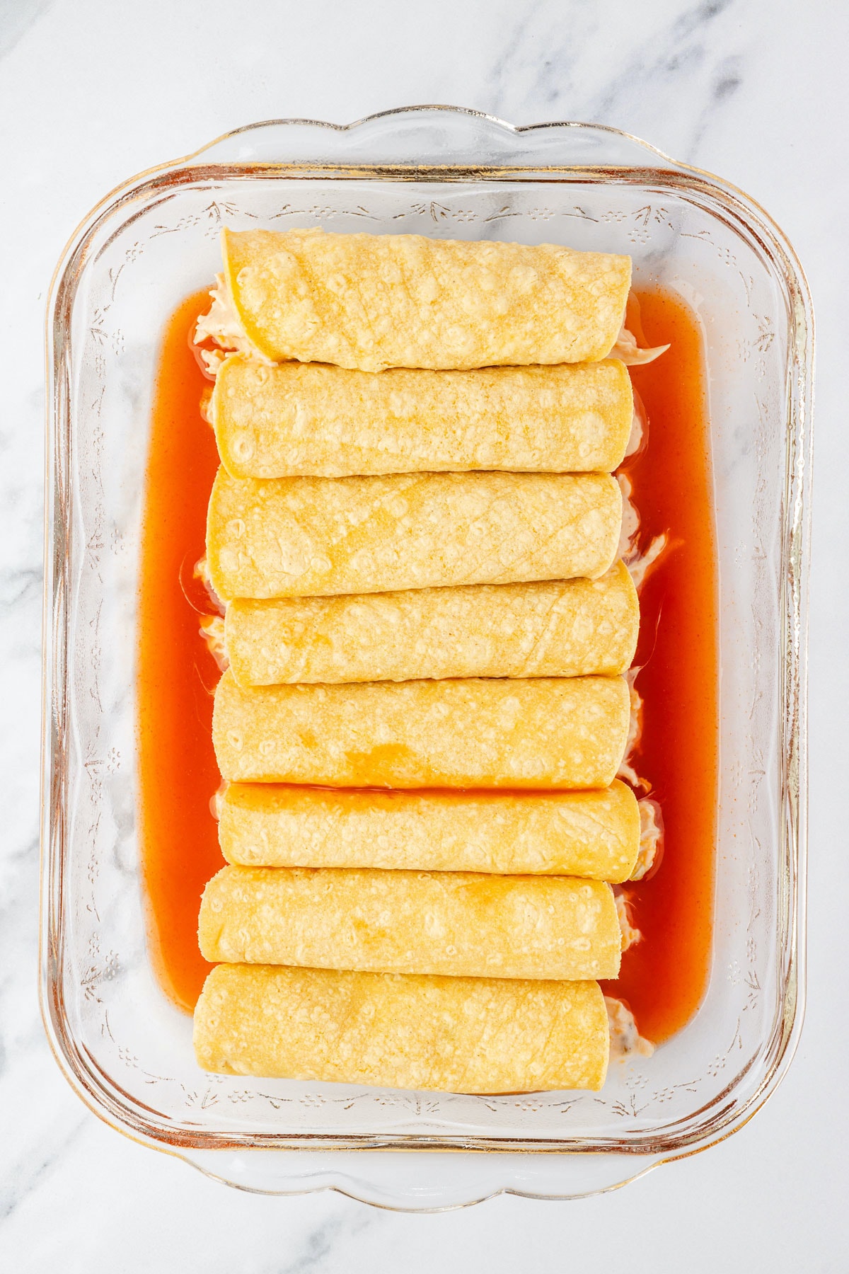 Chicken mixture placed in tortillas, seam side down in baking pan