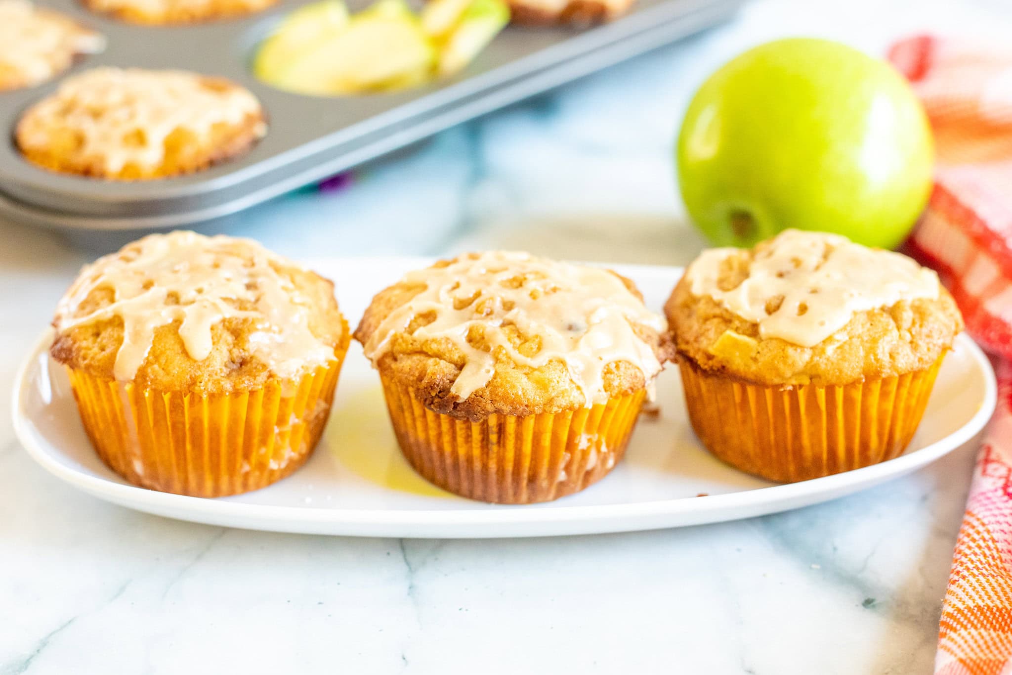 Three caramel apple muffins on a plate, ready to be enjoyed