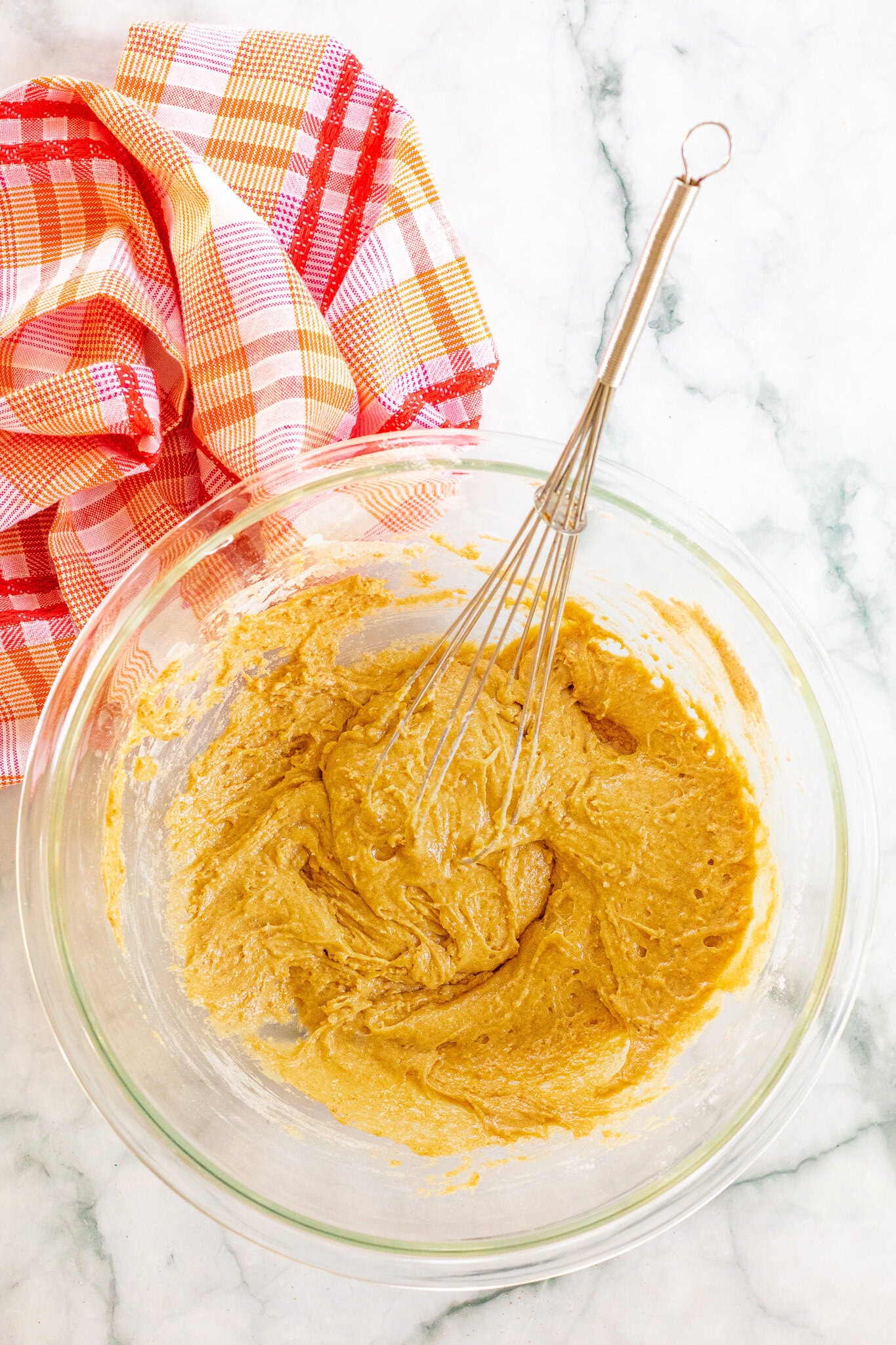 Caramel apple muffin batter in a mixing bowl: egg, milk, vanilla bean paste, and butter.