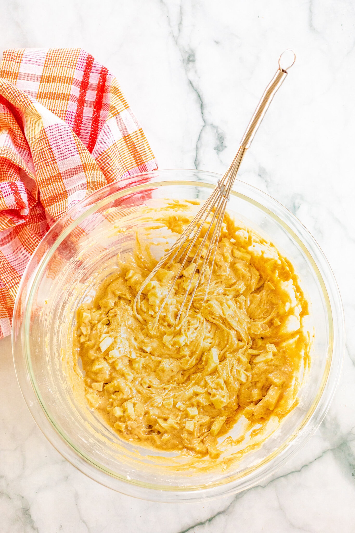 Putting in diced apples into a mixing bowl with muffin batter