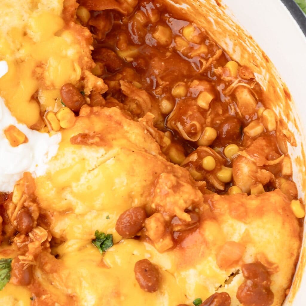 Close up of chicken chili with dumplings and topped with cheddar cheese