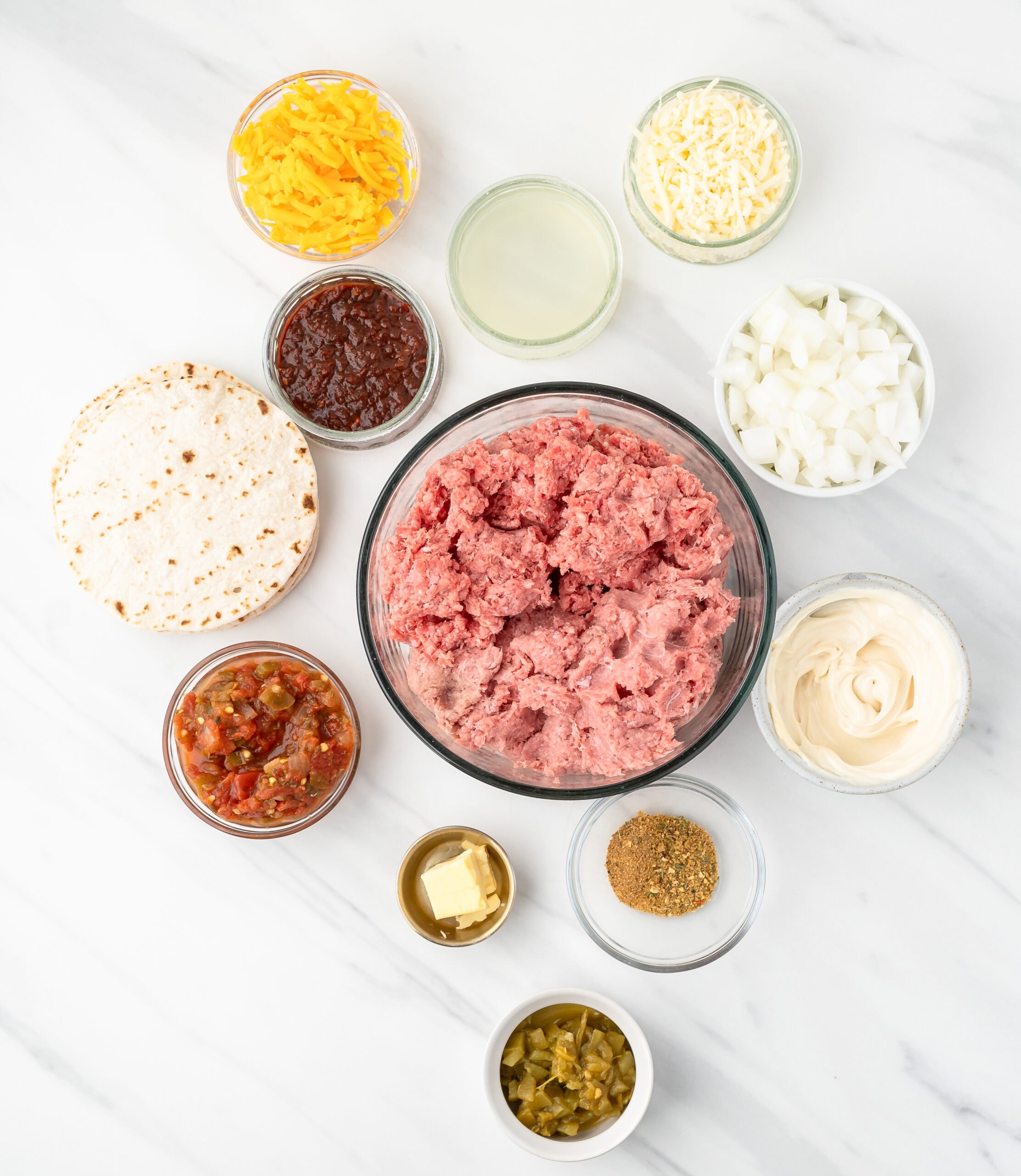 All ingredients to make quesadilla burgers: ground turkey, ground beef, diced green chili's, diced onion, mayo. salsa, tortillas, chipotles in adobo sauce, pepper jack cheese, cheddar cheese, cumin, steak seasoning, butter, lime juice, chili powder.