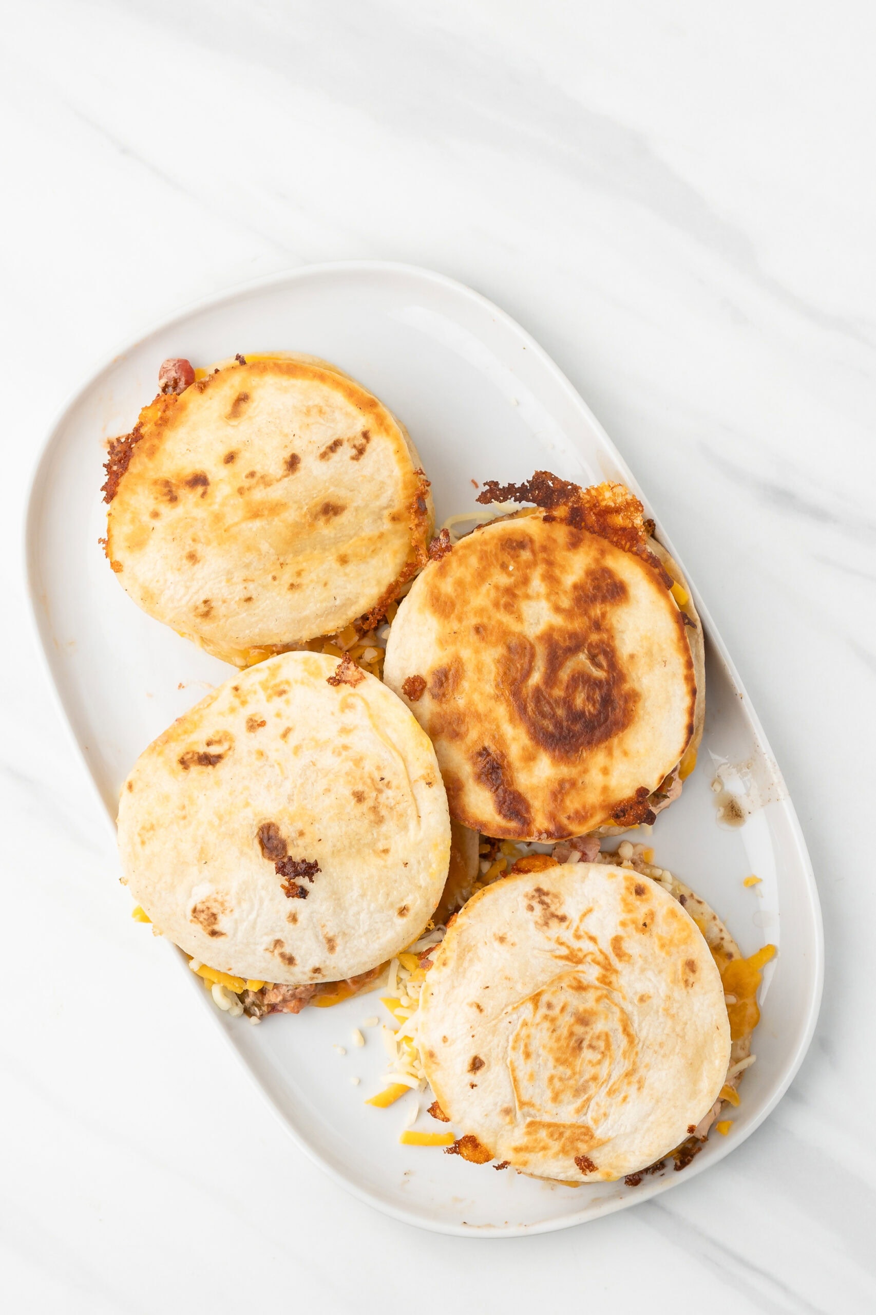 Four quesadilla burgers all put together on a plate
