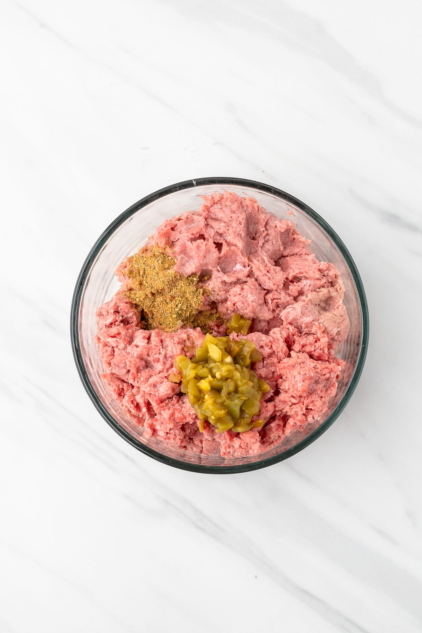 Ground turkey and ground beef in a bowl with diced green chilies