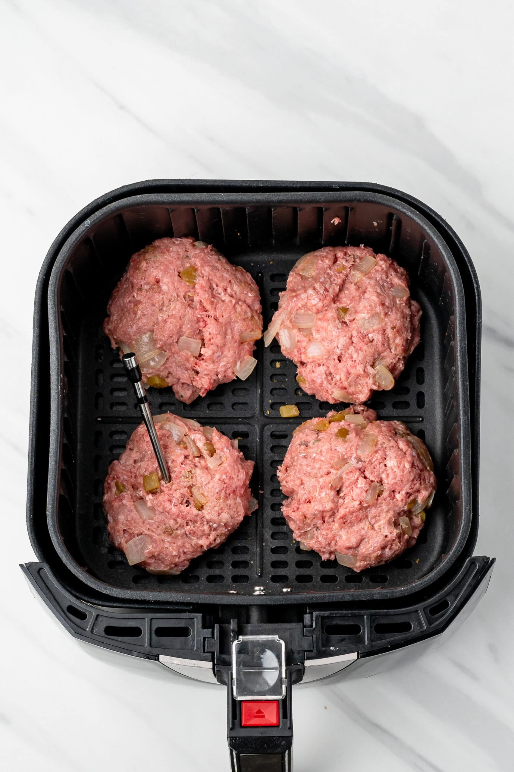 Quesadilla burgers placed in an air fryer, ready to cook them