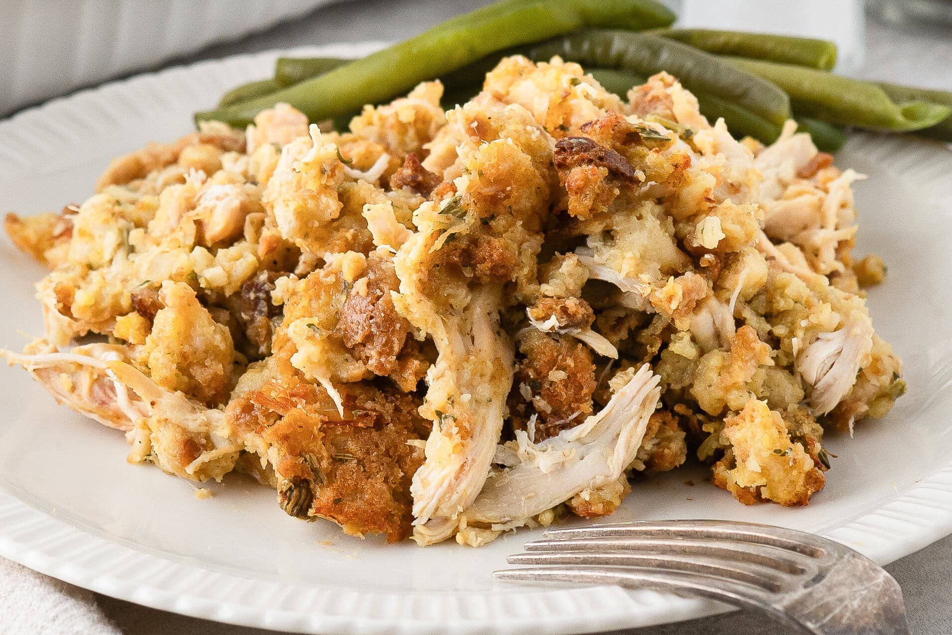 Stove top stuffing and Rotisserie chicken on a plate with a fork and a side of green beans