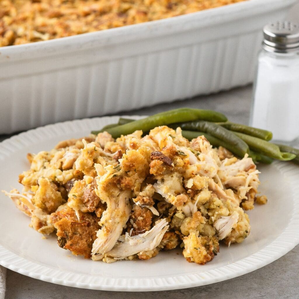 A plate of stove top stuffing and chicken with a side of green beans