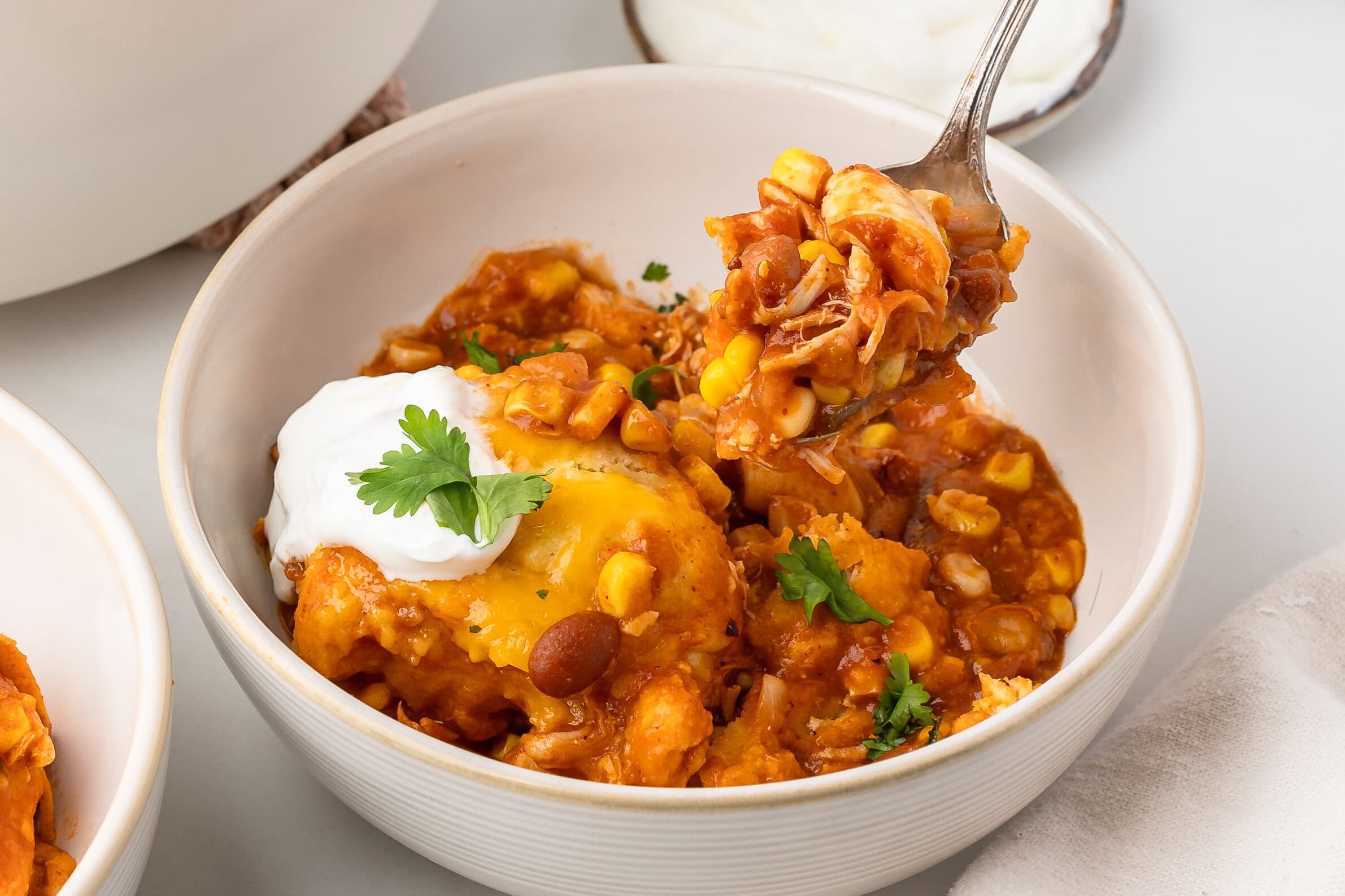 Chicken chili served into a bowl and a fork is holding up a bite size amount