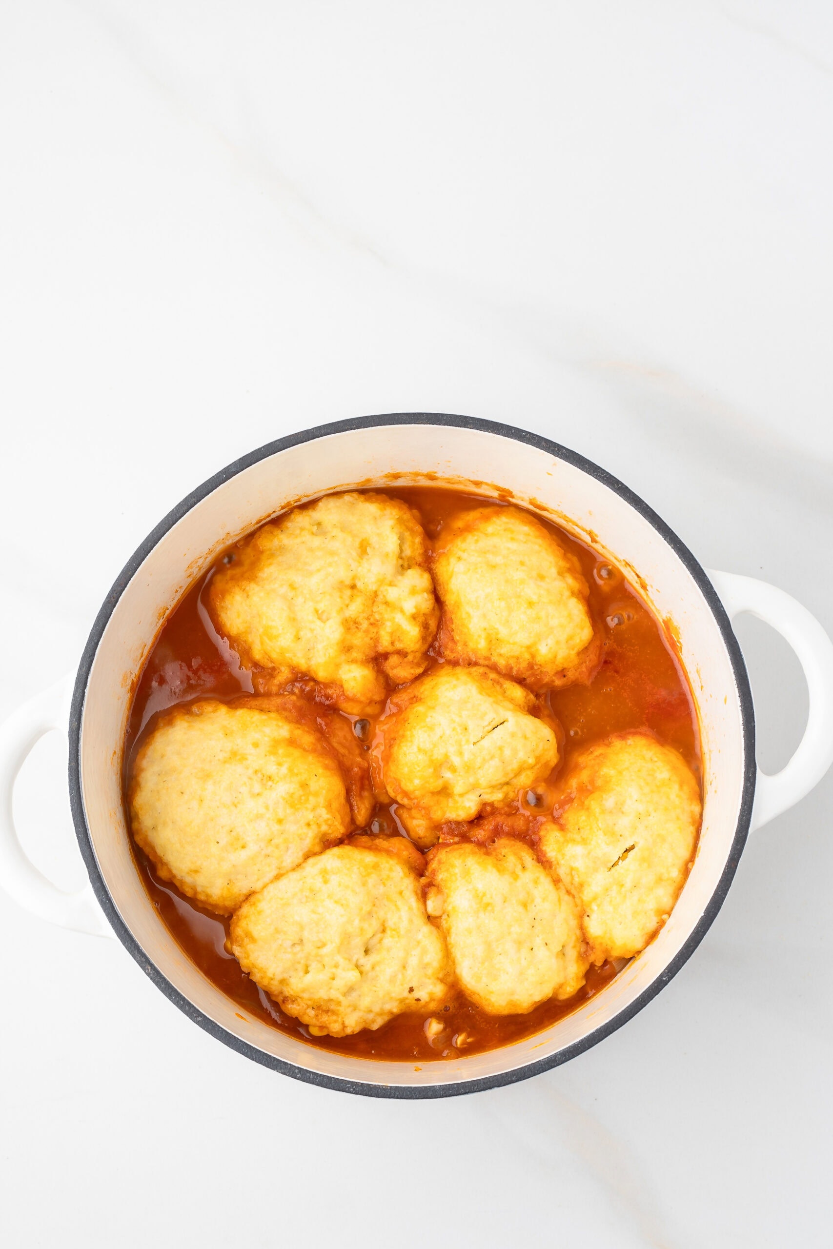 Dumplings all cooked with chicken chili, ready for cheddar cheese to be topped