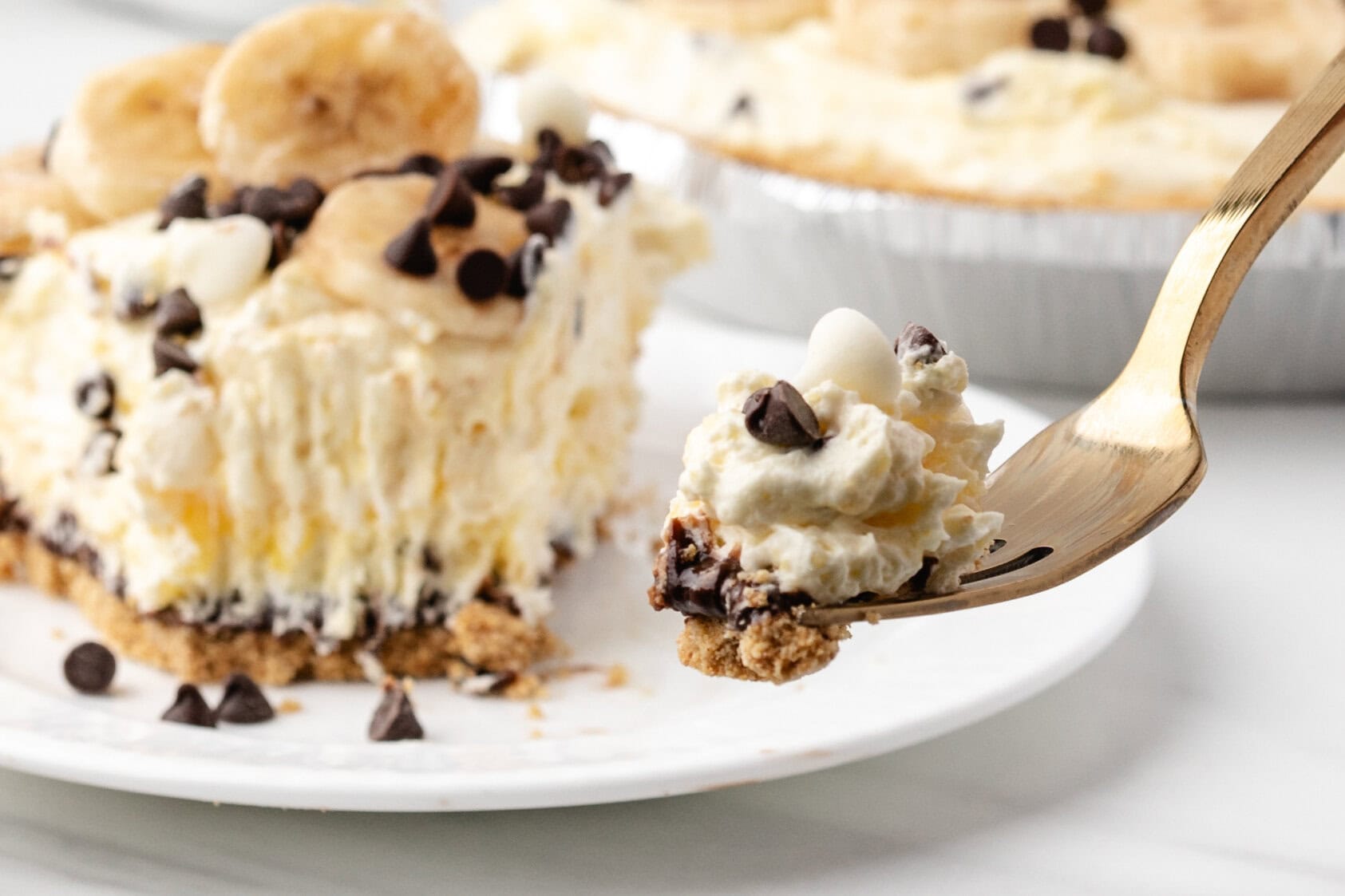 A fork with a bite size amount of the banana cream pie slice.