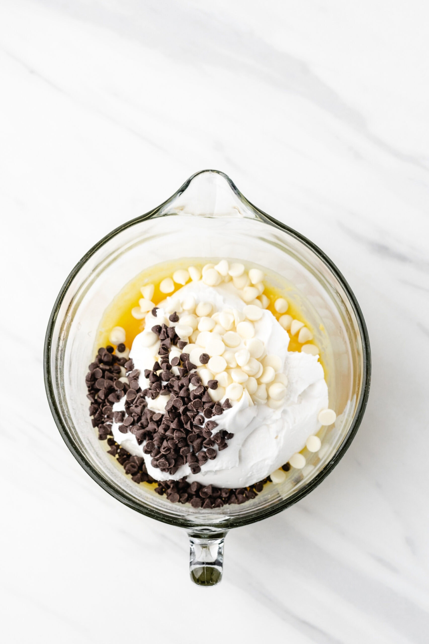 Banana cream pudding in a mixing bowl, with added white and chocolate chips, and cool whip