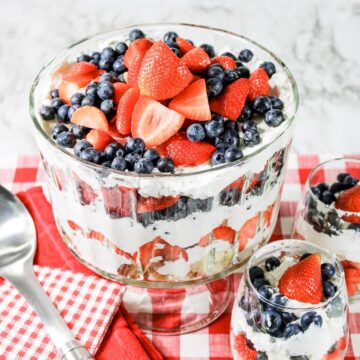a top view of a red, white, and blue berry trifle with cream cheese filling and two small glass bowls of berry trifle
