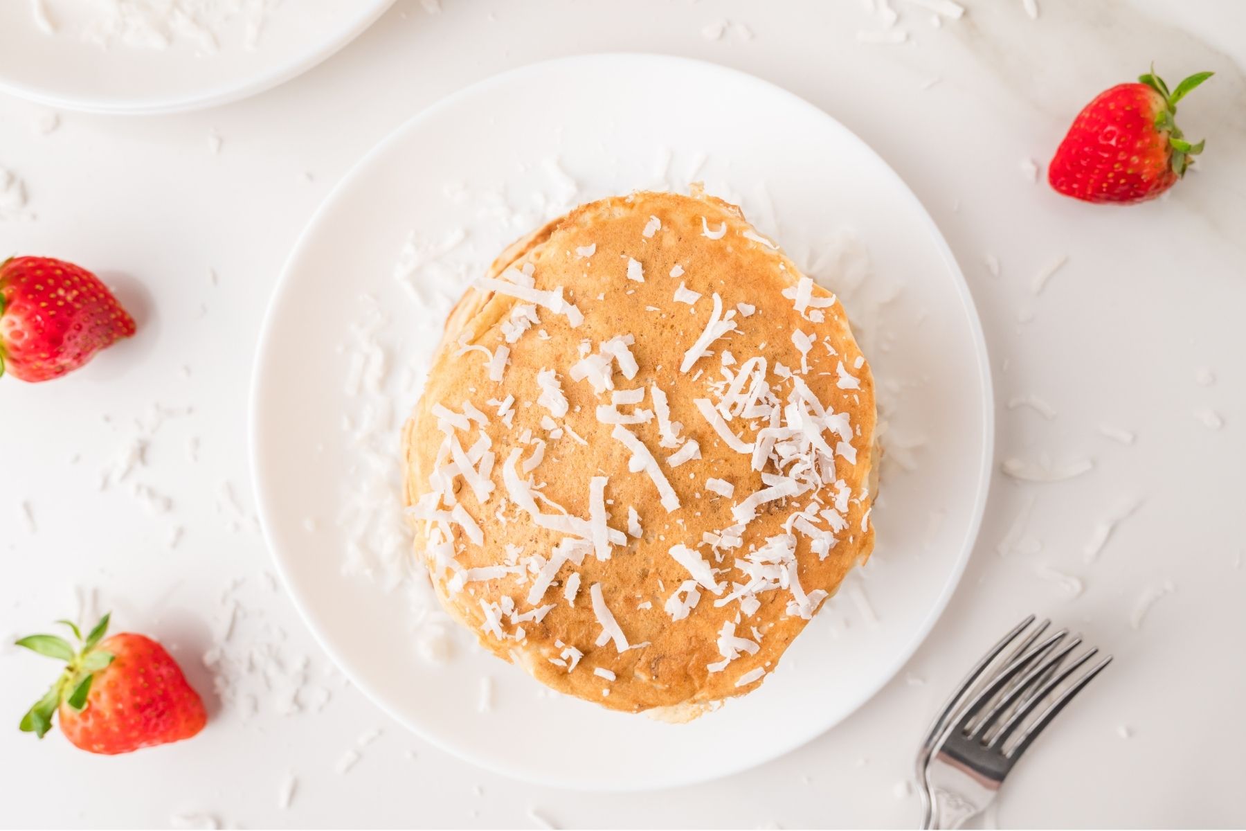 Coconut pancakes topped with syrup and shredded coconut