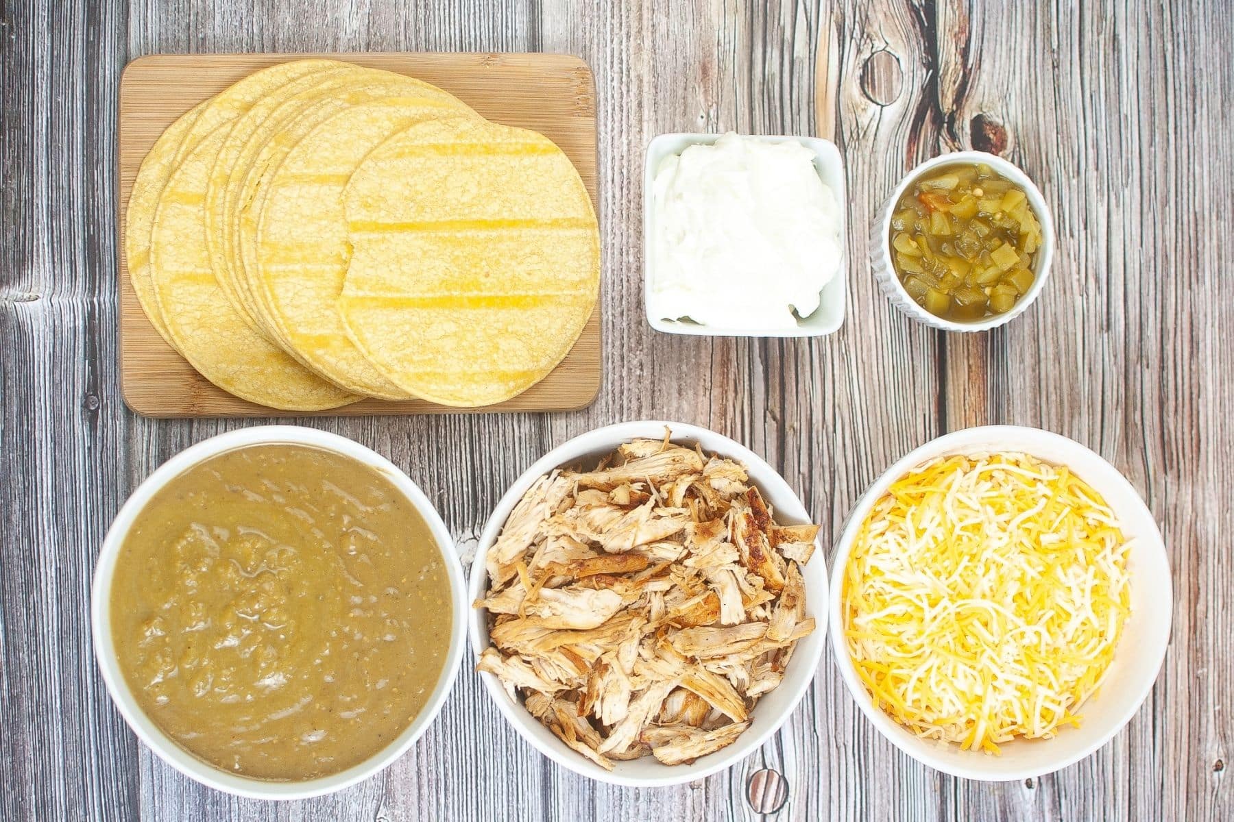 Green chili chicken enchilada ingredients with chicken, tortillas, cheese, and sauce