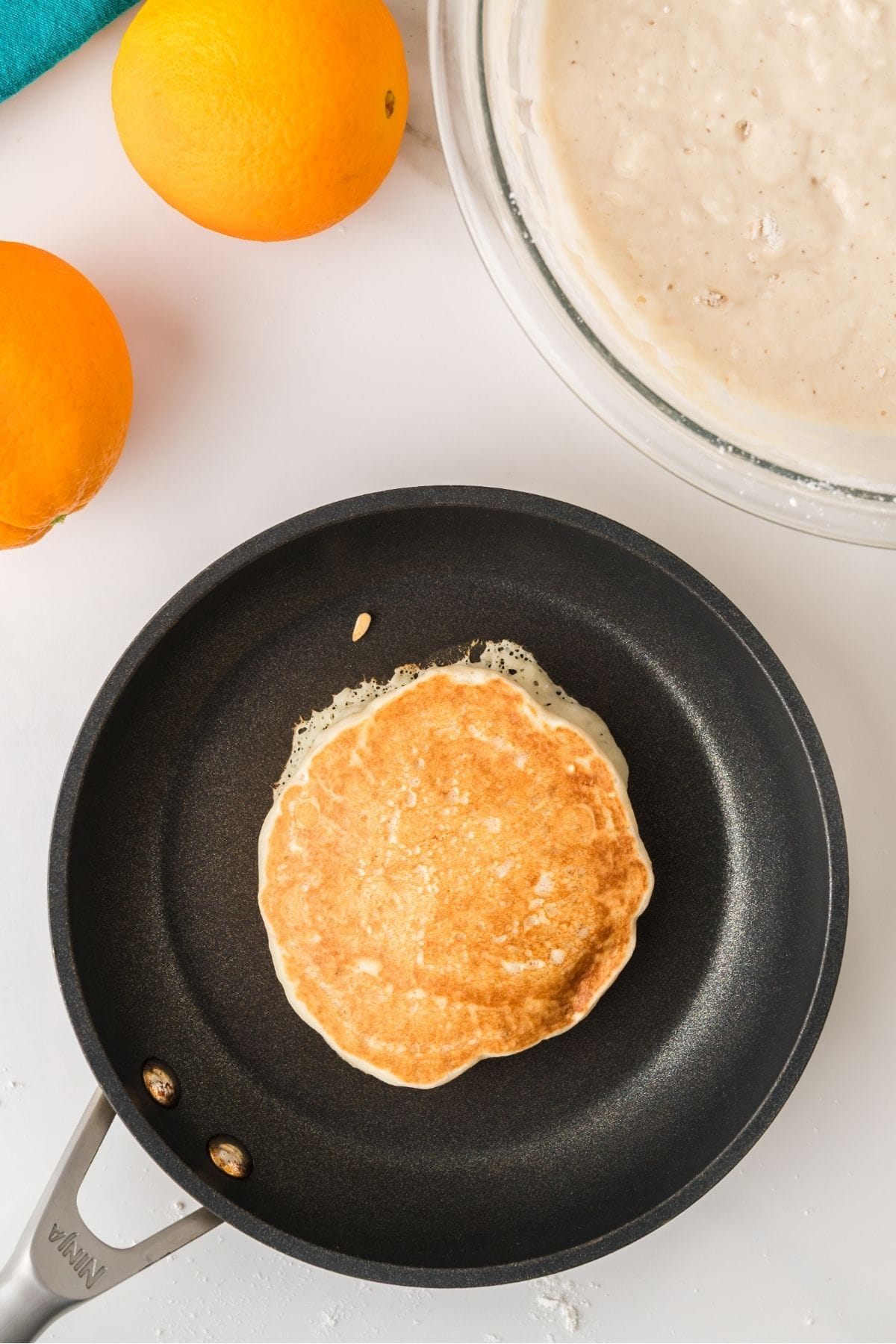 Orange pancake batter poured on hot griddle