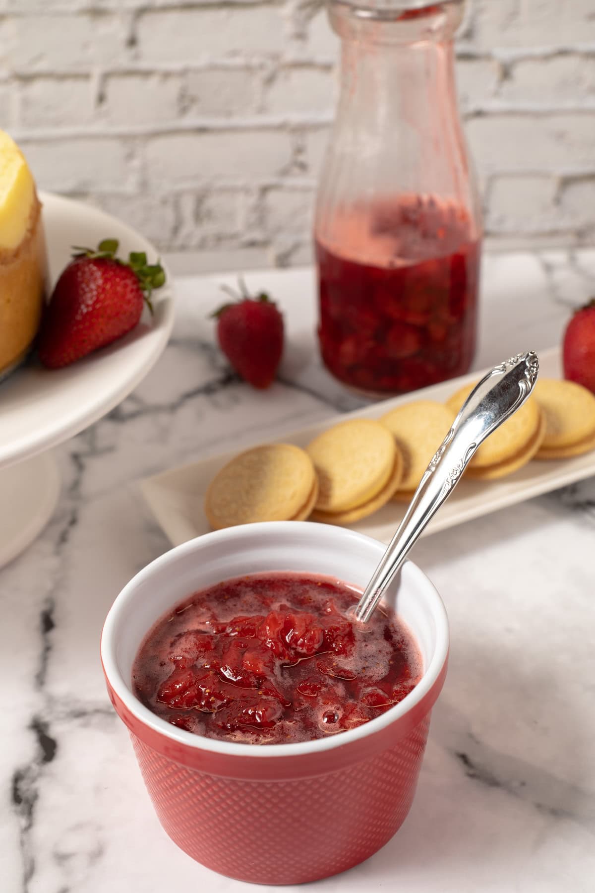 homemade strawberry syrup in a red and white dish with a spoon