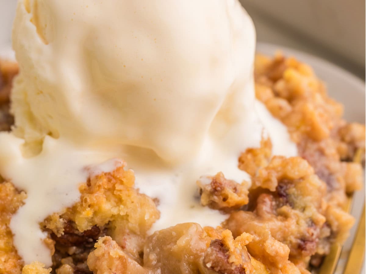 Close-up of caramel apple dump cake with vanilla ice cream and pecans.